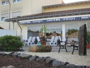 a group of chairs and a bench in front of a building at Hotel Europa in Ramstein-Miesenbach