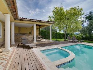 a swimming pool with a deck and chairs next to a house at Villa Caliopa by Interhome in Grasse