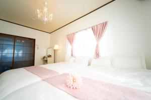 Yokkaichi Large House in Shimizucho nearby Yokkaichi STN في يوكايتشي: غرفة نوم بسرير ابيض عليها ورد وردي