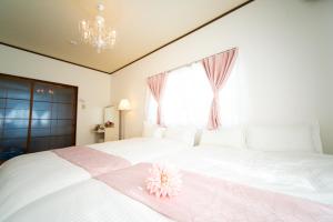 a bedroom with a white bed with a pink flower on it at Yokkaichi Large House in Shimizucho nearby Yokkaichi STN in Yokkaichi