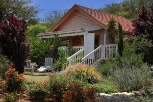 a small house with a porch in a garden at The Beautiful Cabins in Rosh Pinna
