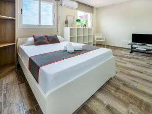 a large white bed in a room with a television at Hostal El Patio De La Luna in Tarragona