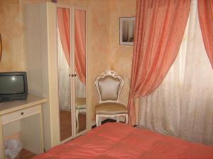 ein Schlafzimmer mit einem Bett, einem Stuhl und einem TV in der Unterkunft Hotel San Marino in Laglio