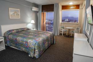 Habitación de hotel con cama, mesa y ventana en Hotel Villa Marina en Ensenada