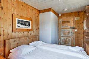 ein Schlafzimmer mit einem weißen Bett an einer Holzwand in der Unterkunft Chalet Speciale - Celerina in Celerina