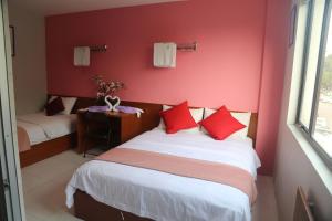 a bedroom with two beds and a red wall at WL HOTEL in Kampung Baharu Sungai Buluh