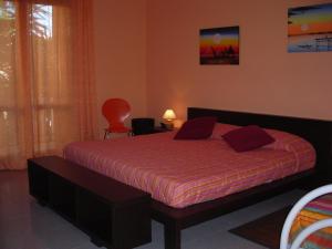 a bedroom with a bed with red sheets and a red chair at B&B CasAnsaldo in Giarre