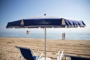 a blue umbrella and chairs on a beach at Hotel Jollino in Pineto