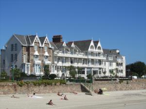 a large building on the beach with people on the beach at Ommaroo Hotel in Saint Helier Jersey