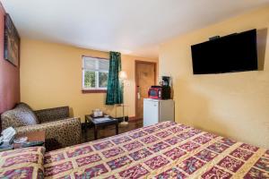 a hotel room with a bed and a couch and a television at Highland Inn New Cumberland in New Cumberland