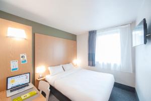 a hotel room with a bed and a desk with a laptop at B&B HOTEL Clermont-Ferrand Nord Riom in Riom