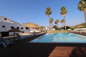 a large swimming pool with chairs and palm trees at Casa do Feitor - Monte da Graça in Elvas