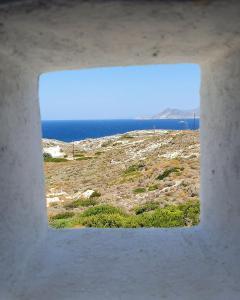 a view of the ocean from a hole in a building at Sarakiniko Rooms in Adamantas