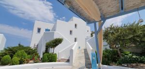 a view of a white building with trees and bushes at Sarakiniko Rooms in Adamantas +37 photos