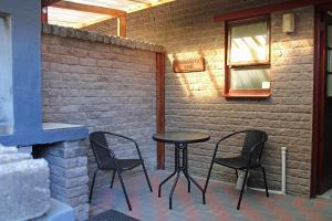 a patio with three chairs and a table and a window at Haven on Hoopoe in Sedgefield
