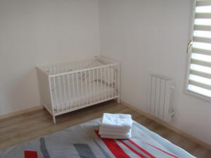 a baby crib in a white room with a window at Maison confortable dans le Périgord pourpre in Lamonzie-Saint-Martin