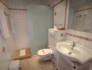 a white bathroom with a toilet and a sink at Apartamentos Parque Mar in Cala d´Or