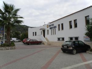 a building with cars parked in a parking lot at Vontzos Hotel in Achladies