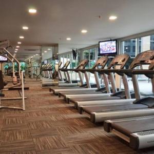 a gym with rows of tread machines in a gym at Casa Grande Residence Tower Angelo in Jakarta