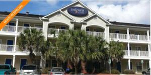a inn with palm trees in front of a building at InTown Suites Extended Stay North Charleston SC - Airport in Charleston