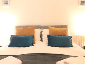 a bed with blue and orange pillows on it at Seaside Cottage with Parking in Worthing