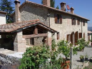 une ancienne maison en pierre avec un jardin en face de celle-ci dans l'établissement Agriturismo San Giovanni, à Cetona