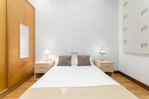a bedroom with a large white bed and two night stands at San Martin 2 - Local Rentss in San Sebastián