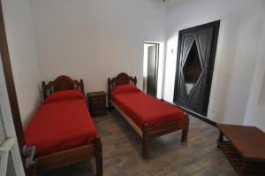 two beds with red covers in a room at Hotel y cabañas FATVIAL 4 de Abril in Tanti