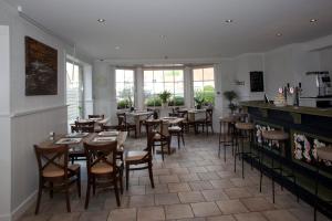 a restaurant with wooden tables and chairs and windows at Huyze Fleur B&B in Knokke-Heist