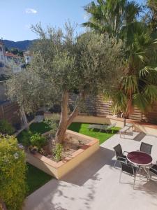 eine Terrasse mit einem Baum, einem Tisch und Stühlen in der Unterkunft meublé au calme à 1 minute de la plage in Banyuls-sur-Mer