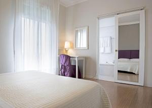 a white bedroom with a bed and a mirror at Hotel Positano in Bassano del Grappa