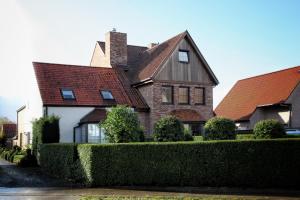 une grande maison avec une haie en face dans l'établissement Huyze Fleur B&B, à Knokke-Heist