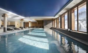 a large swimming pool in a building with windows at Le Lessy M2 in Le Grand-Bornand