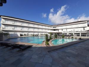 a large building with a swimming pool in front of it at Colônia de Férias Sindi Fast in Peruíbe