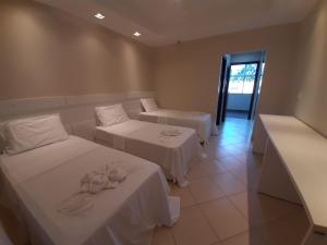 a hotel room with two beds with flowers on them at Colônia de Férias Sindi Fast in Peruíbe +34 photos