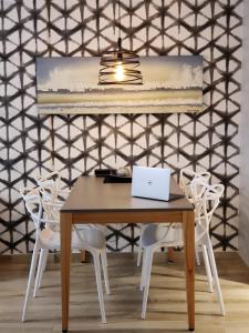 una mesa con sillas blancas y un ordenador portátil. en Montañeses 2888 Flat, en Buenos Aires