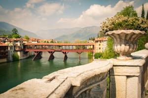 eine Brücke über einen Fluss mit einem Zug. in der Unterkunft Hotel Positano in Bassano del Grappa