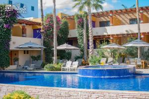 a swimming pool with chairs and umbrellas in front of a hotel at Hotel Los Patios in Cabo San Lucas