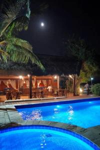 a swimming pool at night with a restaurant at Pousada Peixe Galo in Galinhos