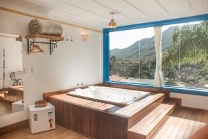 a large bath tub in a room with a large window at Hotel Recanto do Ouro in Ouro Preto