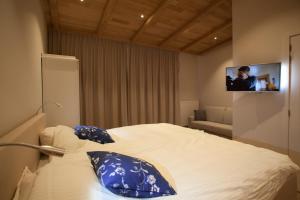 a bedroom with a bed with blue pillows and a tv at Huyze Fleur B&B in Knokke-Heist