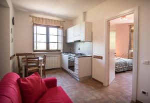 ein Wohnzimmer mit einem roten Sofa und einer Küche in der Unterkunft Agriturismo Dolce Sentire in Assisi