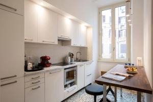 uma cozinha com armários brancos e uma mesa de madeira em Flat Three em Roma