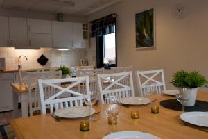 a dining room table with white chairs and a kitchen at STF Valbergsängen Sporthotell in Torsby