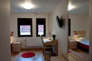 a small room with a desk and a bed at Valbergsängen Hotell & Vandrarhem in Torsby