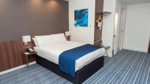 a hotel room with a bed with a blue blanket at Holiday Inn Express Aberdeen Airport by IHG in Dyce