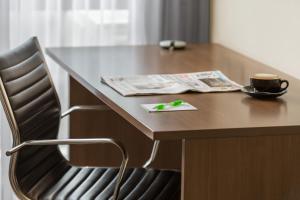 a table with a chair and a cup and a newspaper at Holiday Inn Auckland Airport by IHG in Auckland