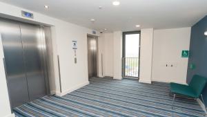 an empty hallway in an office with a green chair at Holiday Inn Express Aberdeen Airport by IHG in Dyce