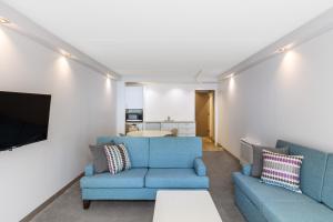 a living room with two blue couches and a tv at Holiday Inn Auckland Airport by IHG in Auckland