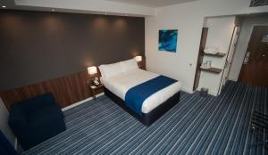 a hotel room with a bed and a chair at Holiday Inn Express Aberdeen Airport by IHG in Dyce